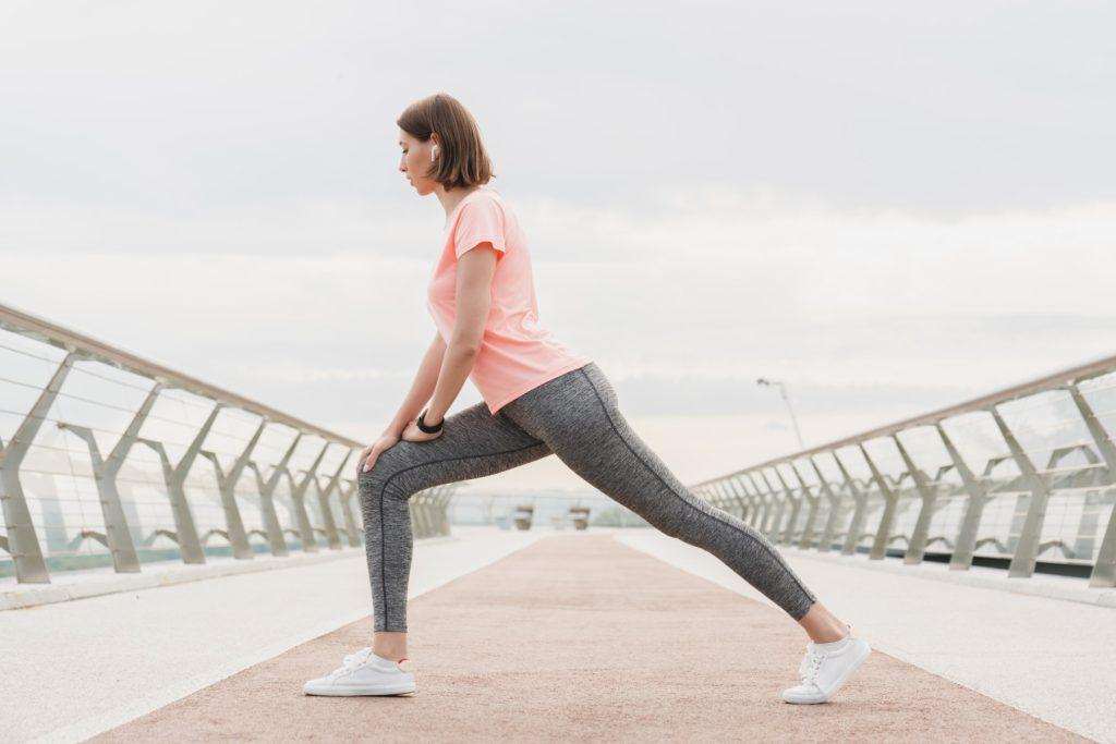 Fit young caucasian female athlete sportswoman jogger stretching before running on city