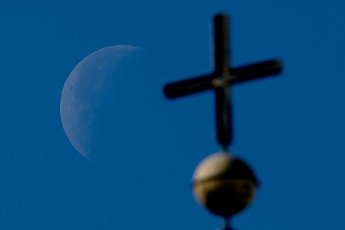 Der abnehmende Viertelmond ist hinter einem Kirchenkreuz zu sehen. (zu dpa: «Flüchtlingsbeauftragte: Nachfrage nach Kirchenasyl steigt») Foto: Swen Pförtner/dpa